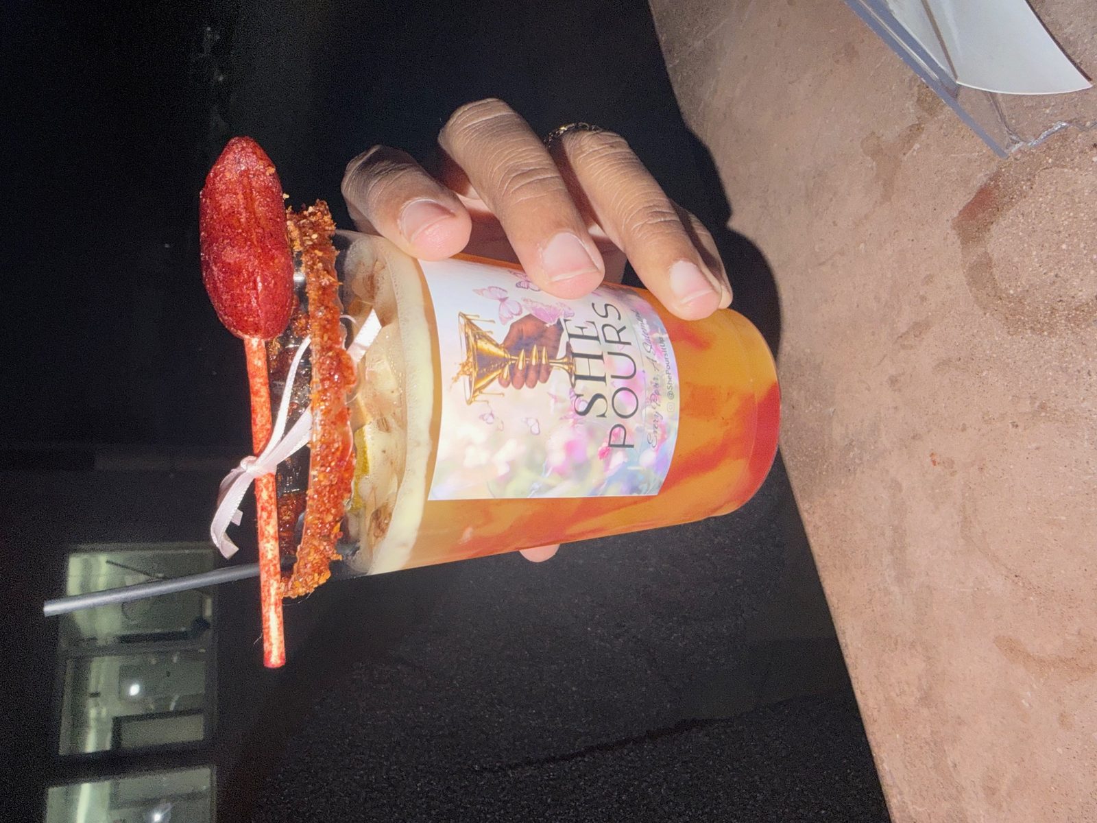 A signature chili-rim cocktail in a She Pours branded cup, held by Ashlee.